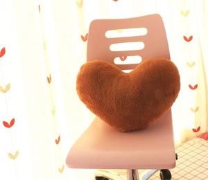 Detailed close-up of a brown heart-shaped plush pillow placed on a pink office chair