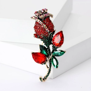 Close-up of vintage rose brooch with red crystal petals and green rhinestone leaves