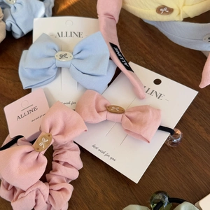 Detail of cotton bow hair clip and scrunchies in pastel colors on wooden background