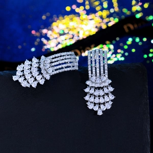 Macro detail of silver drop earrings with pavé crystals on a dark stone surface