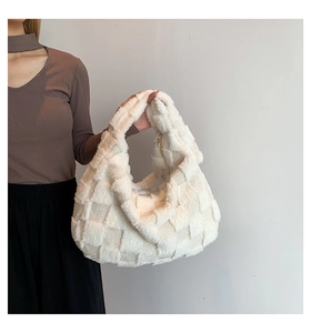 Detail of cream plush tote bag featuring woven pattern and gold metal zipper