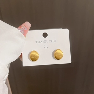 Minimalist egg-shaped gold titanium steel stud earrings shown held on a white thank you card