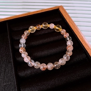 Macro detail of natural citrine and rutilated quartz beads on a black velvet jewelry box
