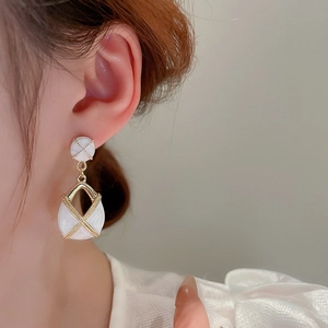Détail de boucles d'oreilles en émail blanc en forme de goutte avec texture dorée