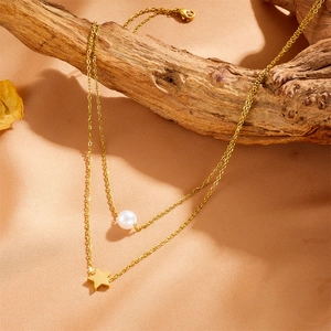 Double-layered gold stainless steel necklace with pearl and star pendant on dry branch