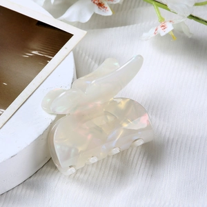 Macro shot of an iridescent cream white butterfly claw clip on a soft fabric background