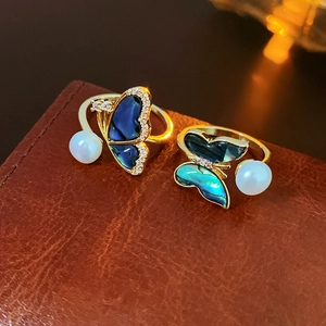 Close-up of gold-plated butterfly rings with blue mother of pearl and freshwater pearls