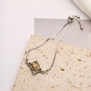Detailed macro view of a skull charm bracelet with red zircon eyes and silver chain