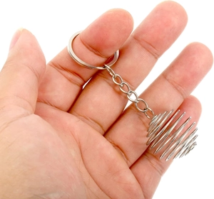 Macro shot of a silver metal spiral cage keychain accessory held in hand on white background