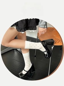 Detail of white mesh socks with floral hollow pattern and ribbed elastic cuffs on Mary Janes