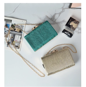 Detailed macro view of pleated evening clutch bags in emerald green and champagne gold tones