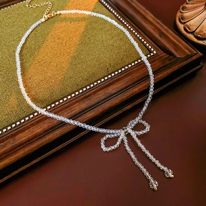 Macro view of crystal beaded bow necklace with dangling pearls on vintage fabric