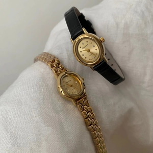 Close-up of vintage small dial quartz watches with gold metal and black leather straps