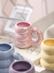 Detail of unique caterpillar-shaped ceramic mugs in pastel pearl pink and blue colors