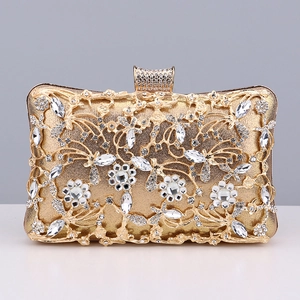Detail of golden evening clutch with hollow metal flowers and sparkling rhinestones