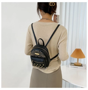 Close-up of black leather punk backpack with gold rivets shown on model's back