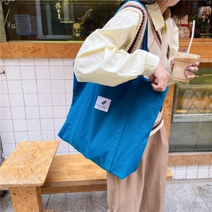 Dark blue canvas tote bag for women featuring a minimalist feather tag on the front