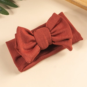 Detail of baby headband featuring large layered knit bow in rust red vintage style