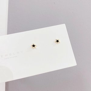Detalle de pendientes de estrella en metal dorado y esmalte negro en tarjeta joya
