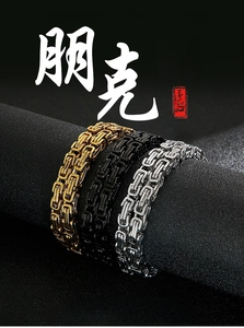 Three-color Byzantine chain necklaces in gold, black and silver on a textured pedestal