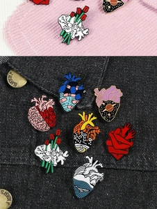 Detailed close-up of creative anatomical heart enamel pins on denim and corduroy fabric