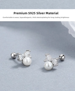 Macro shot of S925 silver bow stud earrings with white pearls and heart-shaped zircons