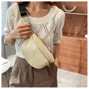 Detail of minimalist cream leather sling bag with gold zippers and adjustable strap