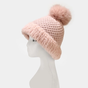 Macro detail of pink knit beanie featuring plush faux fur trim and large fluffy pom-poms