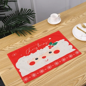 Detail of a red Santa Claus Christmas placemat on a wooden dining table with festive decor