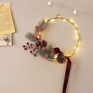 Golden Christmas wreath with warm LED lights, pine cones, berries, and a burgundy ribbon