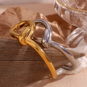 Macro shot of minimalist knotted open bangles in polished gold and silver finishes