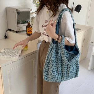 Blue floral crochet canvas tote bag worn by model in a bright lifestyle kitchen setting