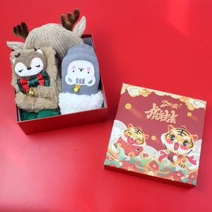 Close-up of reindeer-themed knit hat and plush socks in a festive holiday gift box