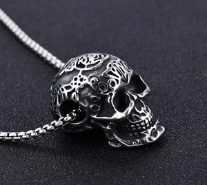 Macro view of gothic skull pendant with floral carvings and silver box chain