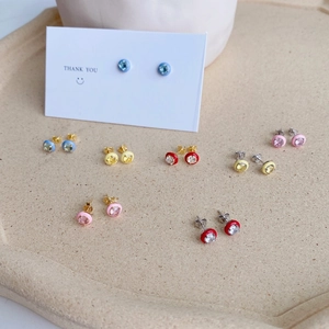Detailed view of colorful zircon heart stud earrings with enamel on a textured tray