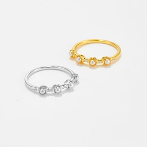 Close-up of gold and silver plated rings set with mini pearls and zircon stones