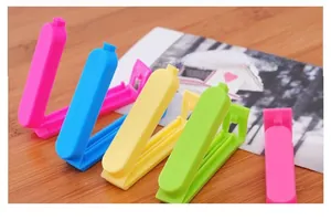 Set of four colorful 7cm plastic food bag sealing clips on a rustic wooden surface