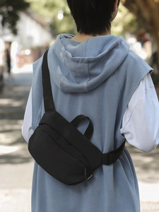 Minimalist black nylon crossbody chest bag for men and women shown on casual outdoor model