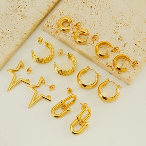 Macro view of five different gold-plated stainless steel earrings on a stone slab