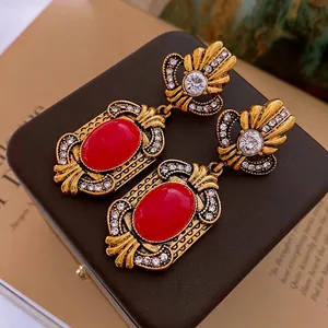 Detail of vintage gold earrings with large red gemstones and baroque floral patterns