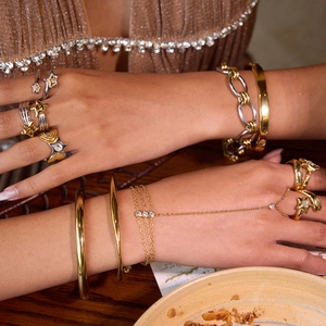 Detail of gold and silver star rings and bracelets worn by model in a natural setting
