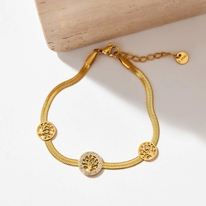 Gold stainless steel Tree of Life bracelet with sparkling zircons on stone background
