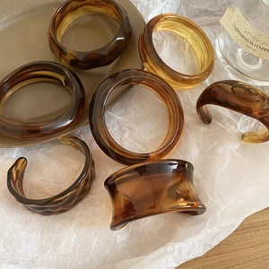 Macro shot of vintage acrylic amber-patterned bracelets on textured paper and ceramic tray