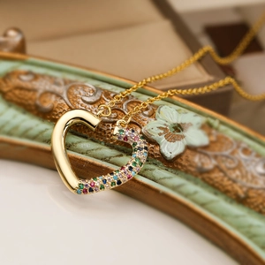 Macro shot of gold-plated heart pendant necklace with colorful cubic zirconia inlay