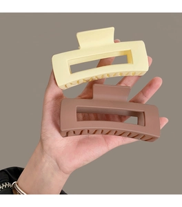 Detailed view of large coffee-colored resin hair claws with a square hollow design