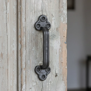 Vintage industrial black cast iron door handle with clover base on rustic wood surface