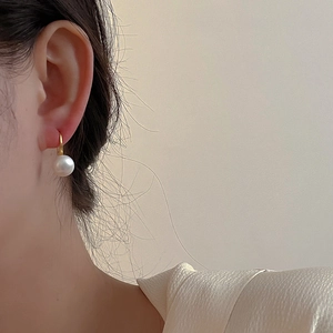 Close-up of elegant 10mm natural freshwater pearl earrings with minimalist gold hooks