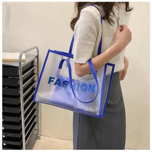 Detail of blue transparent PVC tote bag with leather trim worn by model on shoulder