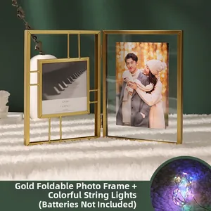 Golden double-fold metal photo frame set with colorful LED string lights on white rug