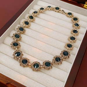 Vintage gold necklace featuring blue flower gemstones and white crystal detailing